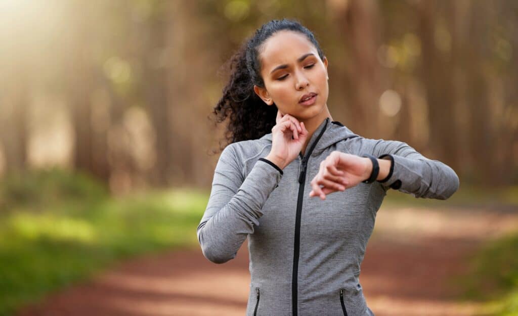 Shot of a woman feeling her pulse while checking her watch