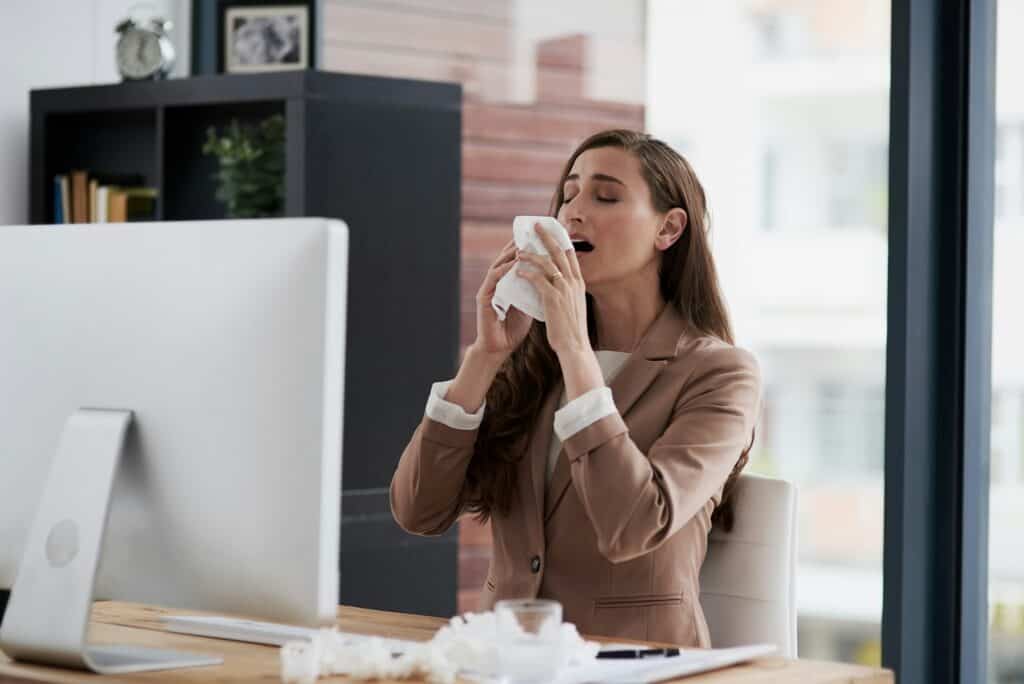 Shot of a young businesswoman suffering with allergies at work